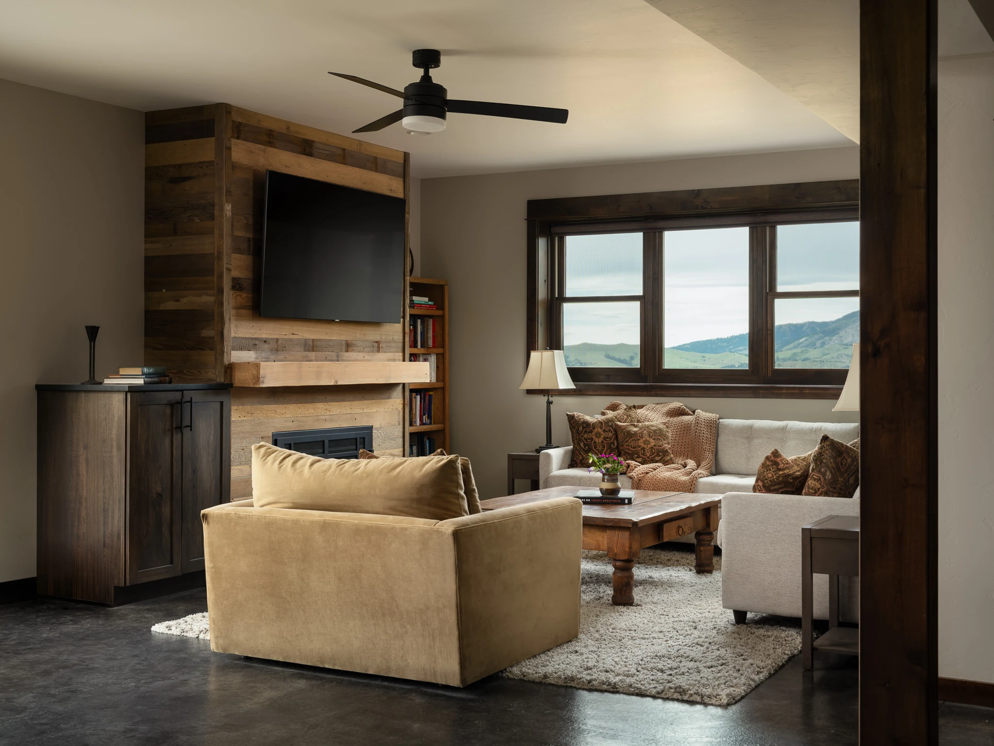 Living room with a reclaimed wood fireplace wall and sectional sofa — interior design photography Livingston Montana, Sam Schlauch Designs